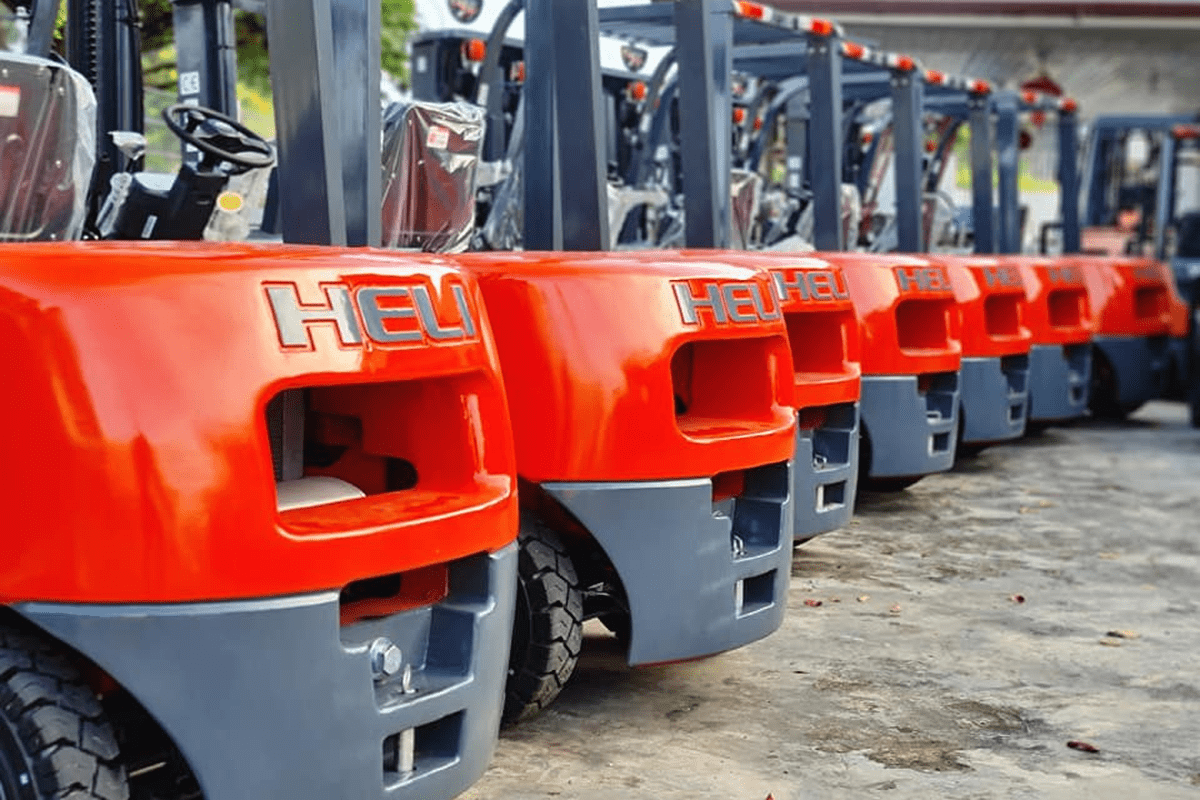 A lineup of red forklifts parked in an organized manner within a spacious parking lot.